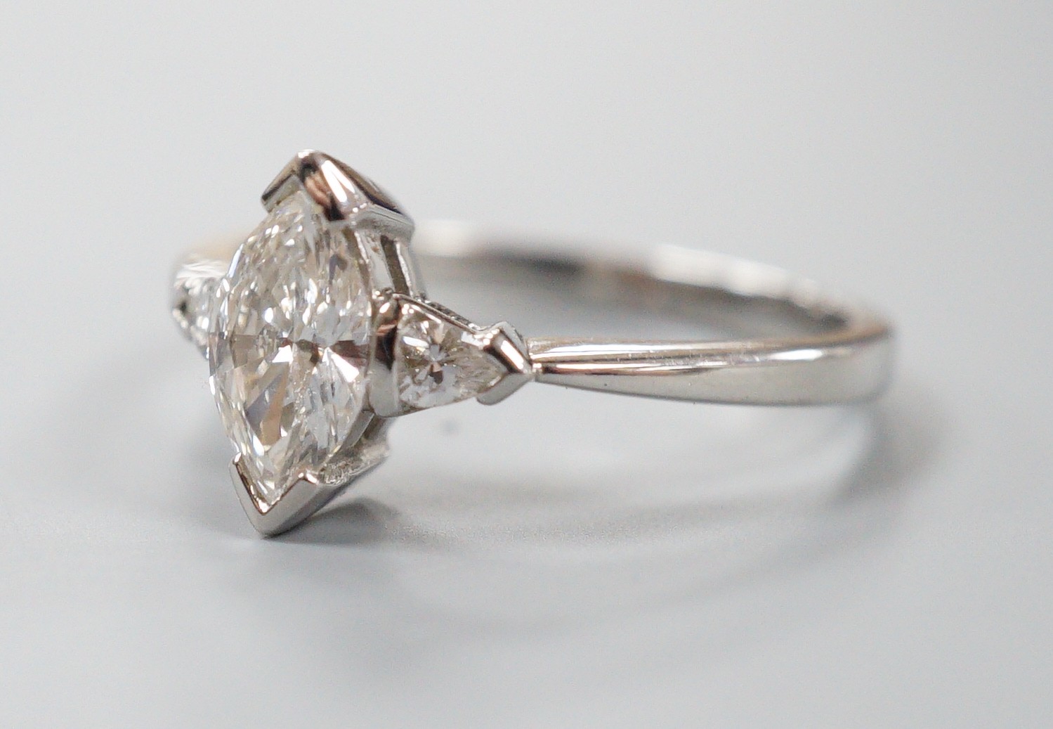 A modern platinum and single stone marquise diamond set ring, with two stone pear cut diamond set shoulders, size M, gross weight 3.8 grams